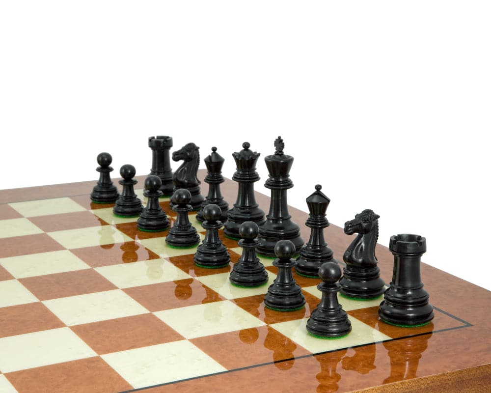 Handcrafted ebony chess pieces positioned on a luxury chessboard with detailed opulent moulding and classic Staunton look.