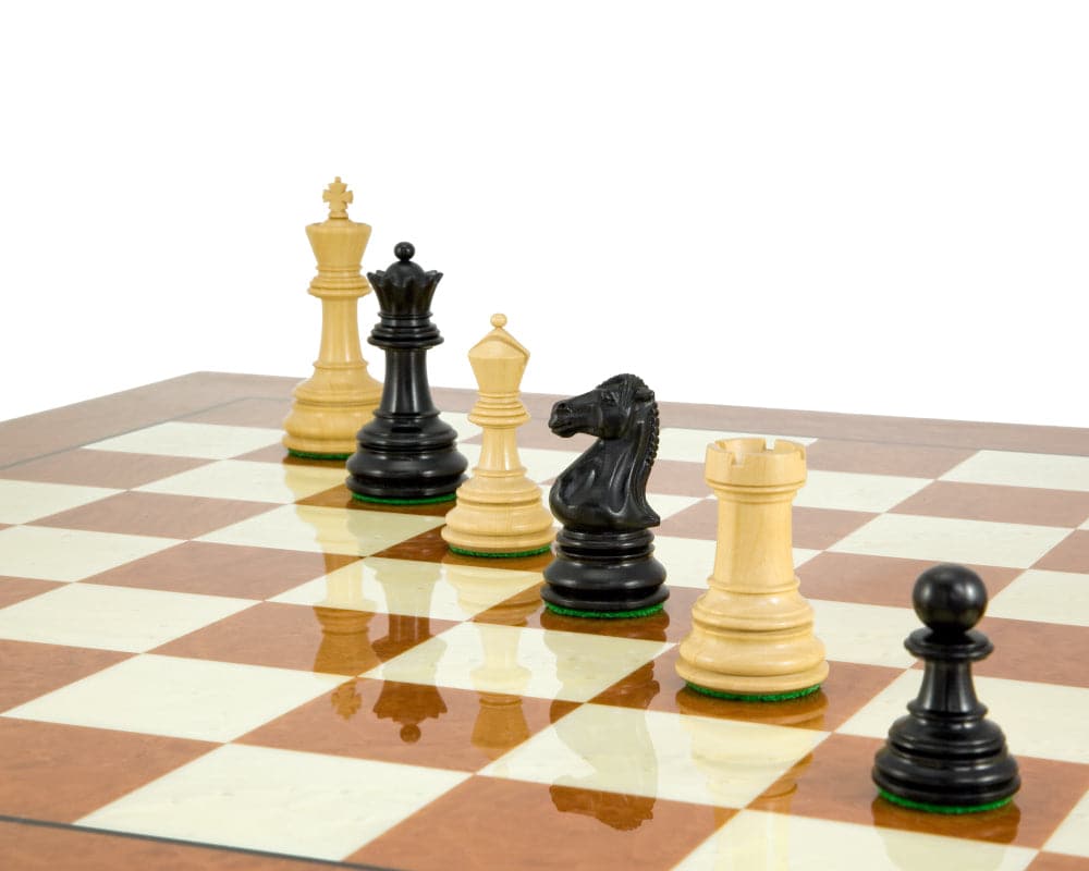 Handcrafted ebony and boxwood chess pieces in Staunton style on a chessboard with a reflective surface.