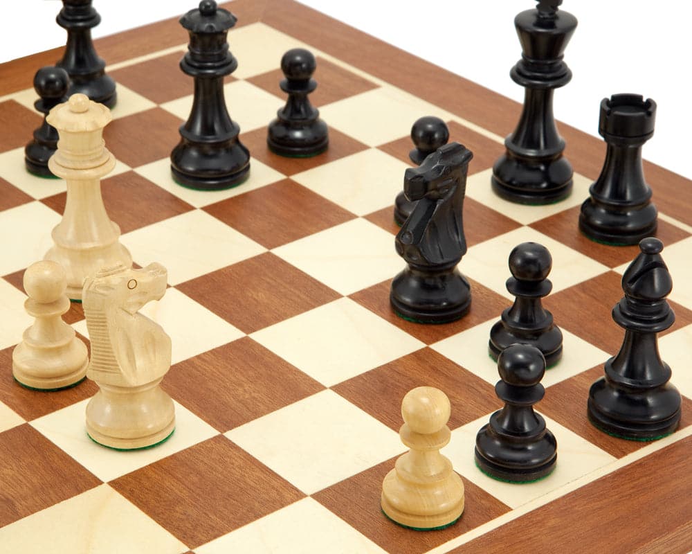 Close-up of French Knight Black Mahogany Chess Set pieces on a mahogany and maple board, featuring handcrafted weighted chessmen.