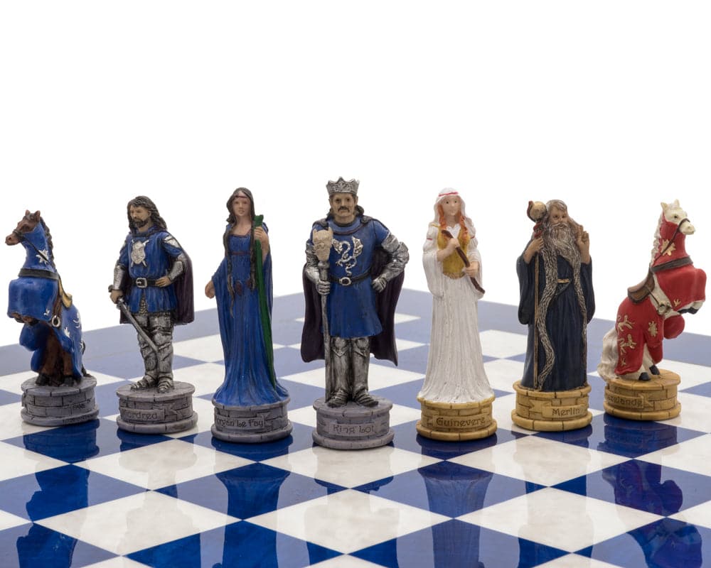 Hand-painted Arthurian chess pieces on blue and white chessboard: King Arthur, Merlin, knights, queen, and horses in luxury chess set.